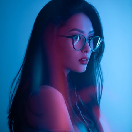 Ázsiai lány szemüvegben, kék háttér előtt